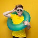 Nachdenklicher Mann mit einem Schwimmring, der sich am Kopf kratzt, auf gelbem Hintergrund